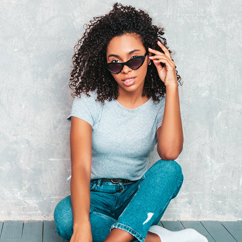 Woman sitting down, wearing fall clothes and wearing sunglasses